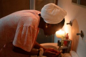 This is the image of a pregnant woman washing her face at the sink due to morning sickness and fatigue