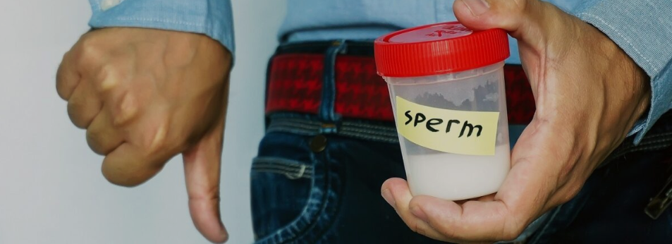 This is an image of a man holding a sample container labeled "sperm" with a thumbs-down gesture, representing concerns about low sperm count and male fertility.
