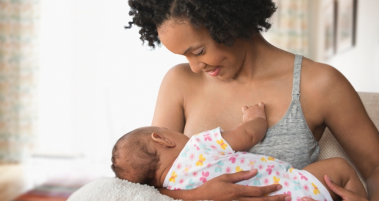 Mother breastfeeding her baby while sitting calmly at home, showing a close bonding and feeding moment