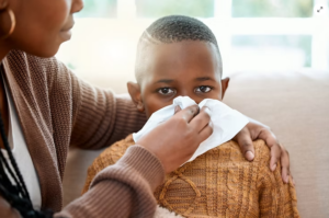 An image of a mother helping her son blow his nose