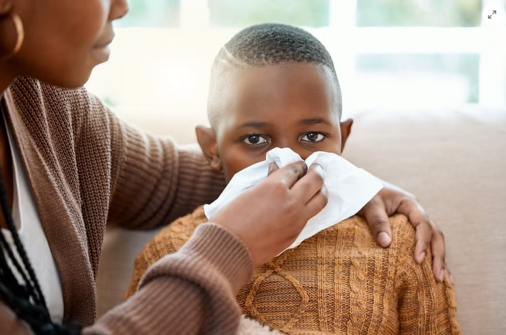 An image of a mother helping her son blow his nose