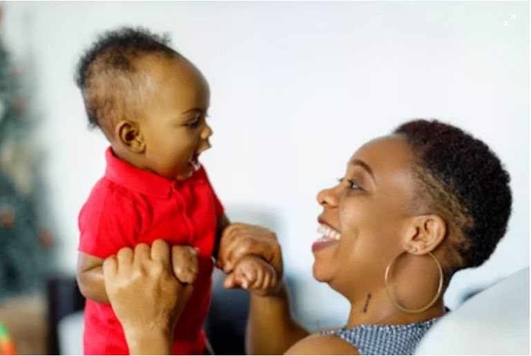 New mother holding her newborn baby close while sitting comfortably, showing a calm postpartum bonding moment