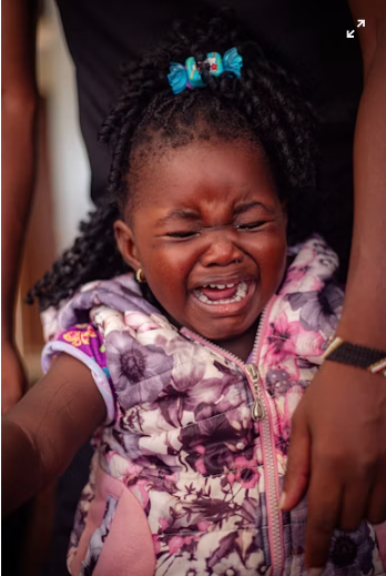 An image of a young child crying while holding a parent's hand, showing signs of separation anxiety before being apart.