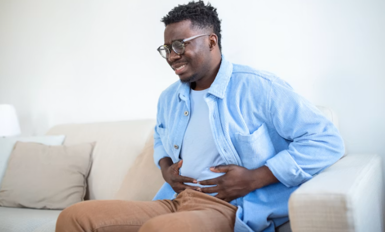 An image of a man holding his upper stomach in pain, representing symptoms of acid reflux or a stomach ulcer.