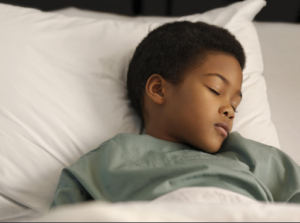 Sleeping toddler lying peacefully in bed, illustrating childhood bedwetting and healthy sleep habits