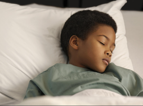 Sleeping toddler lying peacefully in bed, illustrating childhood bedwetting and healthy sleep habits
