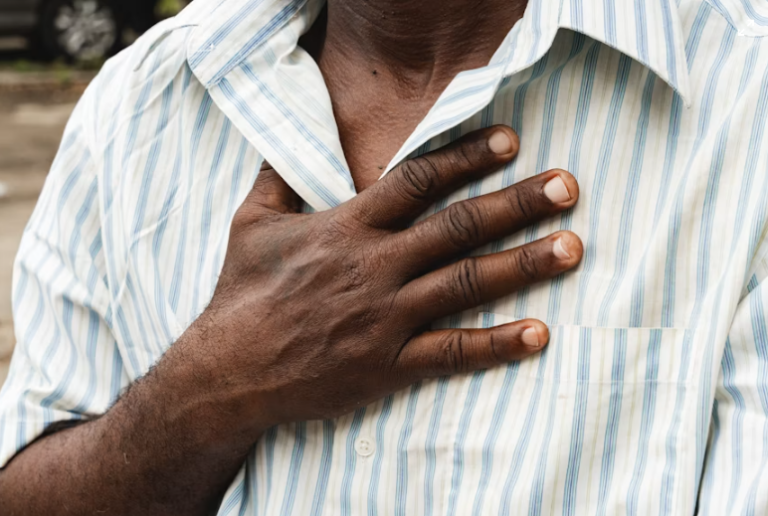 An image of a man holding his chest while experiencing heartburn