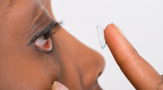 An image of a woman holding a contact lens on her fingertip close to her eye